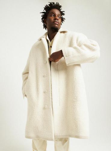 Manteau en maille de laine mélangée écru, pull MAISON KITSUNÉ et pantalon SANDRO.